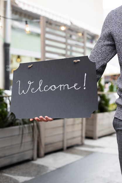 Free photo front view man holding welcome sign