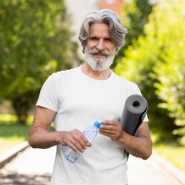 Front view man holding yoga mat