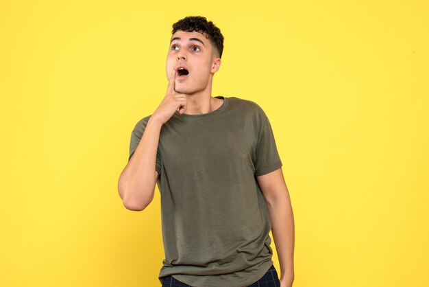 Front view of the man holds finger on his cheek and looks up