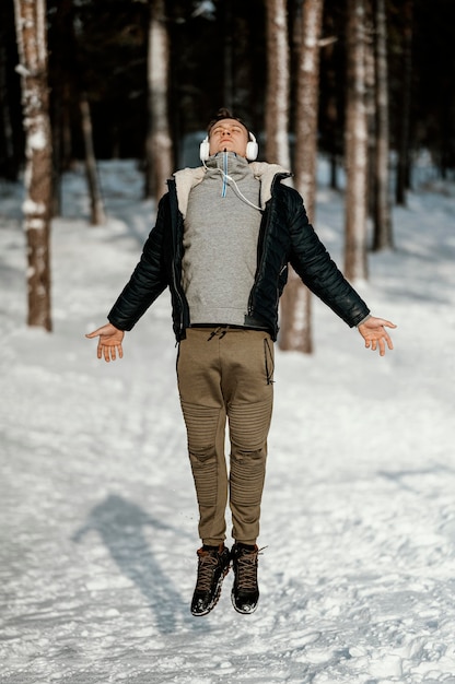 Вид спереди человека, прыгающего на открытом воздухе на природе зимой