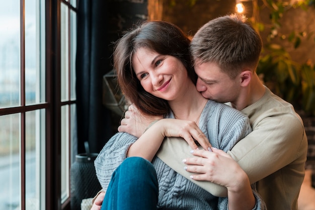 Free photo front view of man kissing smiley girlfriend on the neck