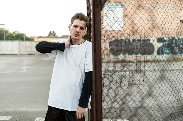 Front view man leaning against a fence