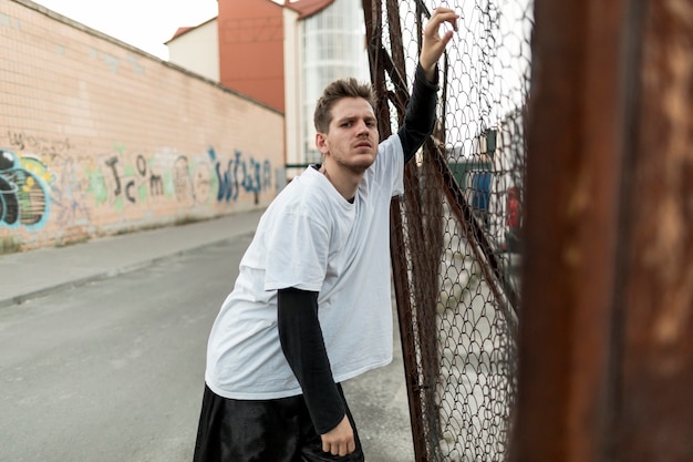 Free photo front view man leaning against a fence