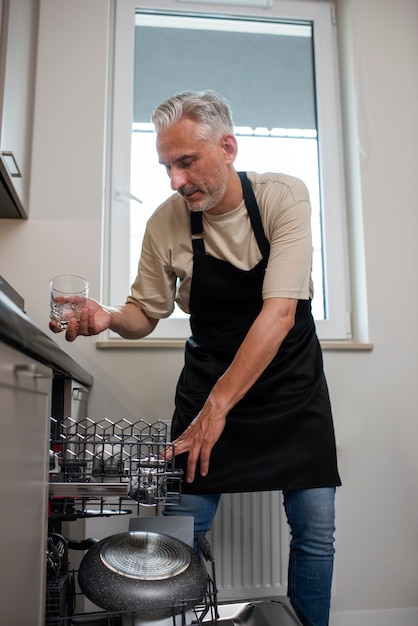 Front view man loading the dishwasher