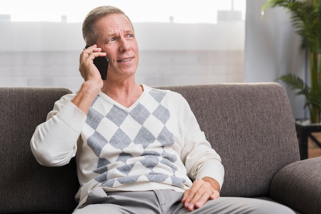 Free photo front view of man looking away and talking at phone