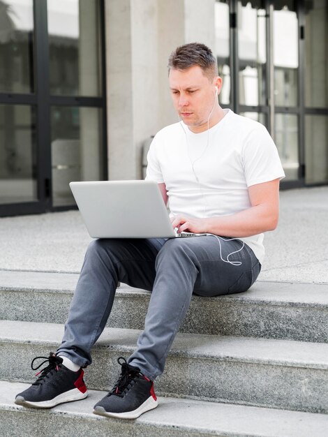 ノートパソコンで作業する手順を屋外で男の正面図