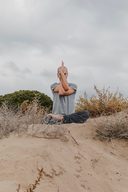 Vista frontale dell'uomo fuori meditando mentre si fa yoga