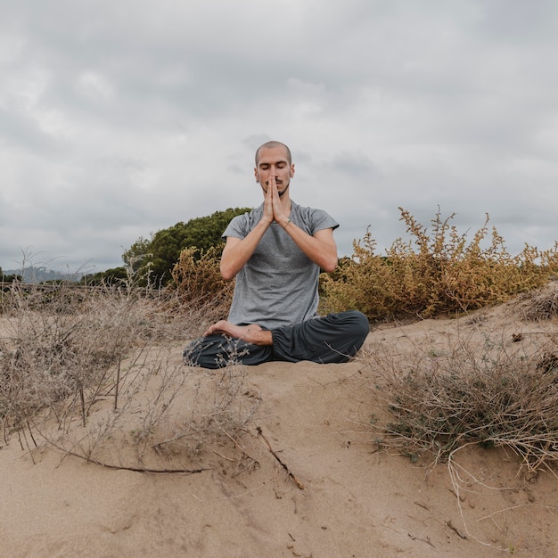 Free photo front view of man outside relaxing while doing yoga