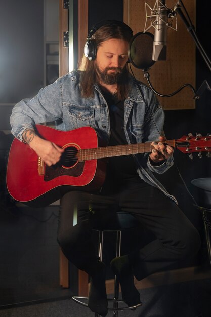 Front view man playing the guitar in studio