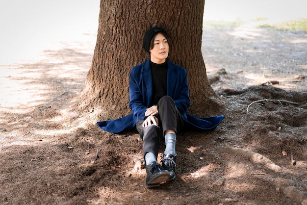 Free photo front view of man posing in the park near tree