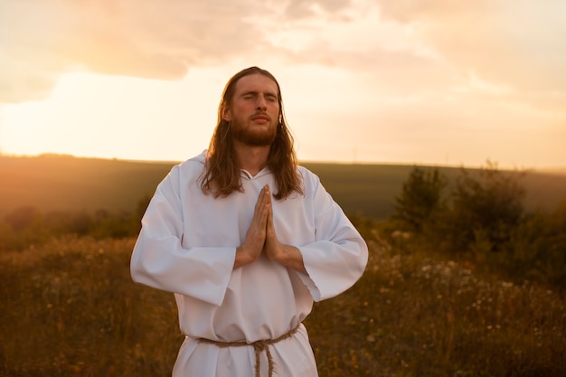 Вид спереди мужчина молится на открытом воздухе