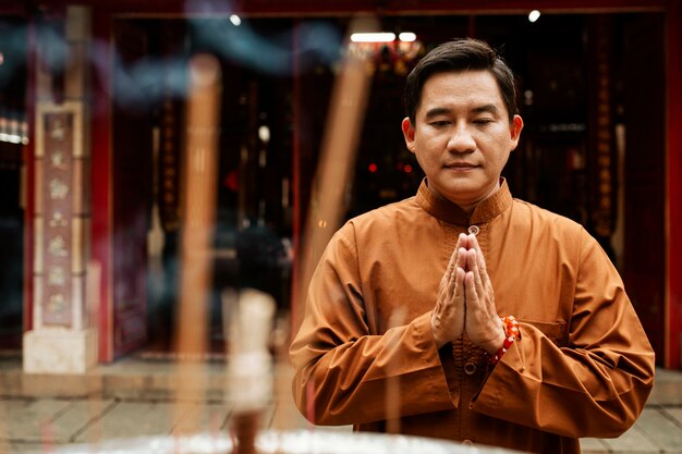 Front view of man praying at the temple with incense