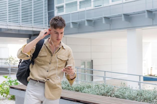 Free photo front view of man putting on earphones outdoors