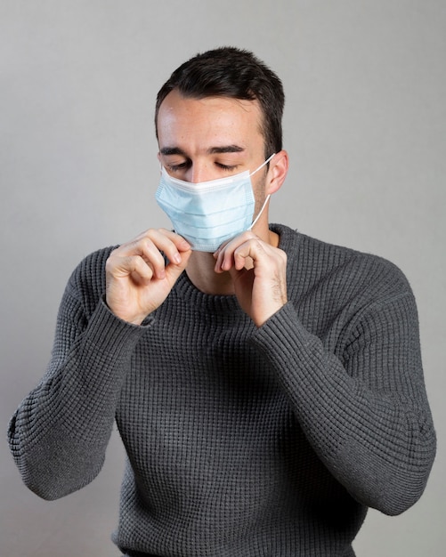 Free photo front view of man putting a medical mask on for prevention