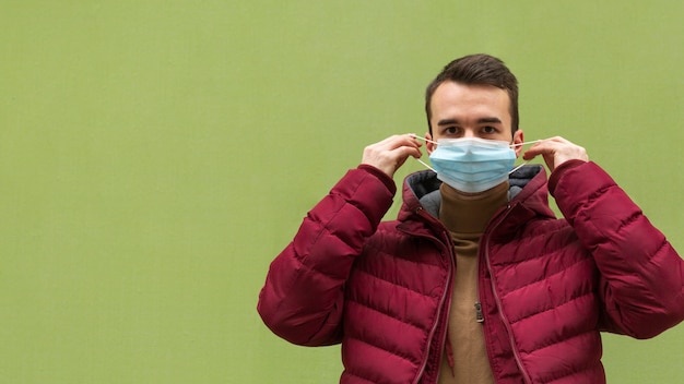 Front view of man putting on medical mask with copy space