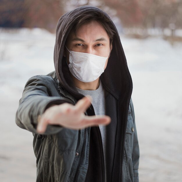 Front view of man reaching for someone while wearing a medical mask