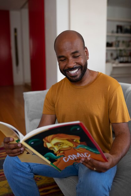 Вид спереди мужчина читает комиксы дома