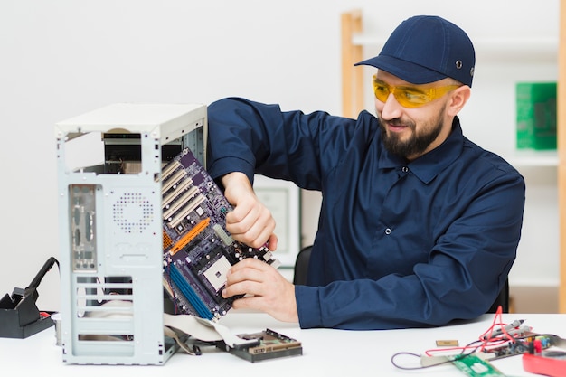 Foto gratuita uomo di vista frontale che ripara un computer