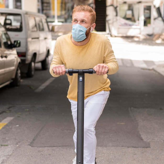 Uomo di vista frontale che guida il suo scooter all'esterno