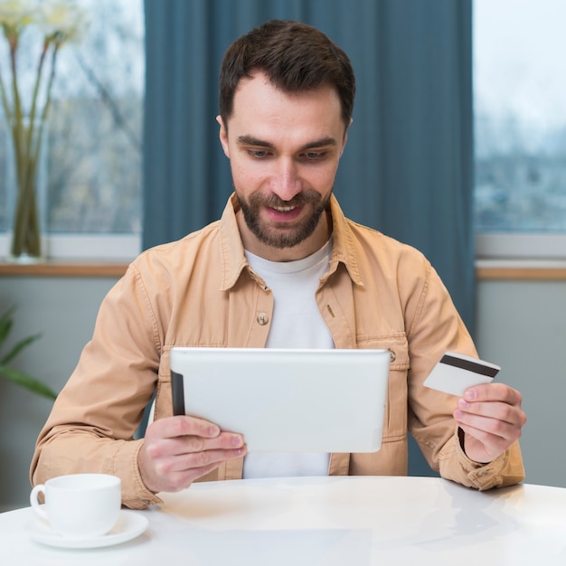 Free photo front view of man shopping online using tablet and credit card