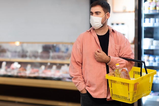 Foto gratuita uomo di vista frontale che acquista con la maschera