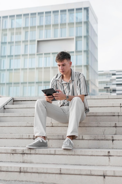 Free photo front view of man on steps outdoors looking at tablet