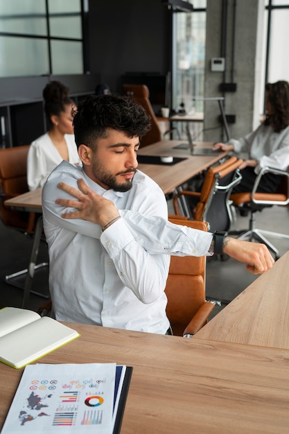 Foto gratuita uomo di vista frontale che si allunga al lavoro