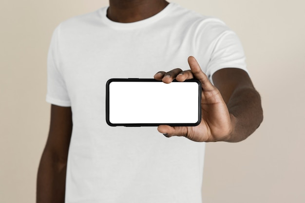 Front view of man in a t-shirt holding smartphone with copy space