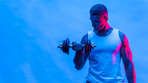 Front view of man in tank top holding weights with copy space