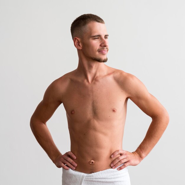 Вид спереди человека в полотенце, позирующего без рубашки