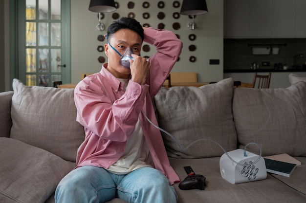 Free photo front view man using nebulizer at home