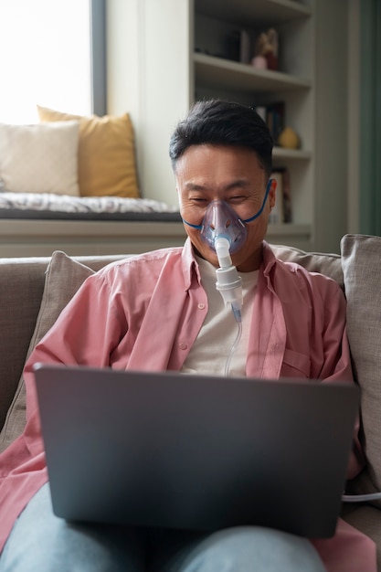 Foto gratuita uomo di vista frontale che usa il nebulizzatore a casa