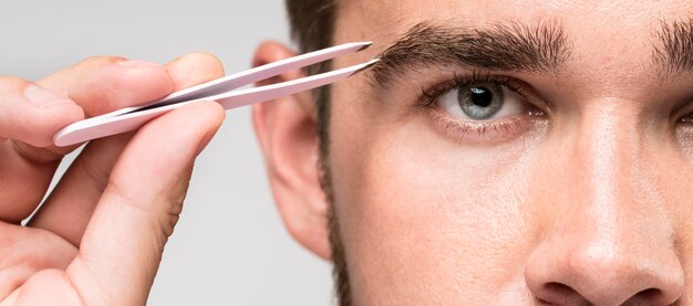 Front view man using a pair of tweezers close-up