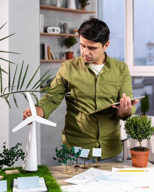 Free photo front view of man using tablet next to an eco-friendly wind power project layout