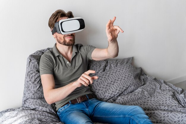 Front view of man using virtual reality headset in bed