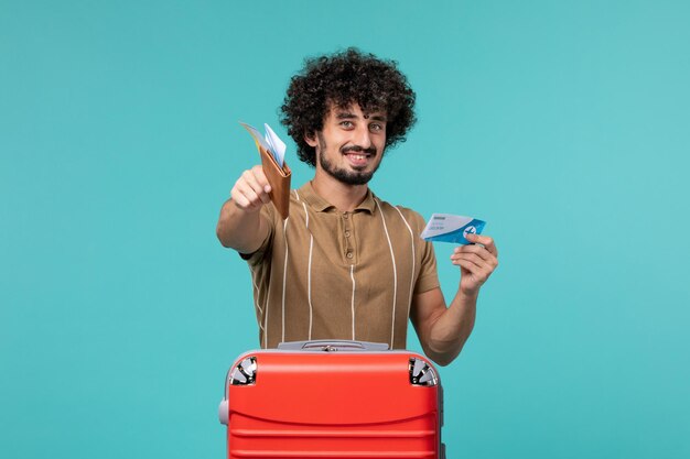 Front view man in vacation holding his tickets on blue