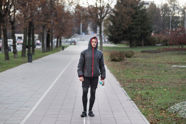 Вид спереди человека, идущего и держащего бутылку воды