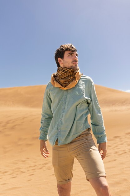 Front view man wearing scarf in desert