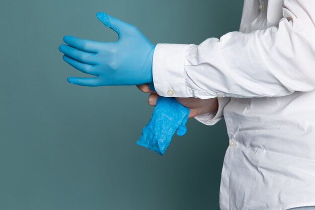 A front view man in white medical suit and blue gloves on the blue desk