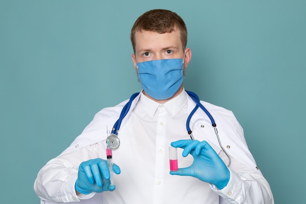 Вид спереди человек в белом медицинском костюме синие перчатки и синяя маска на синем пространстве