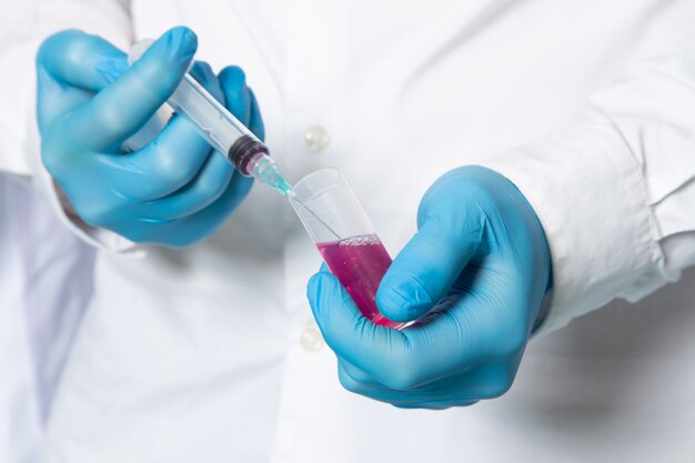 A front view man in white medical suit filling up injection