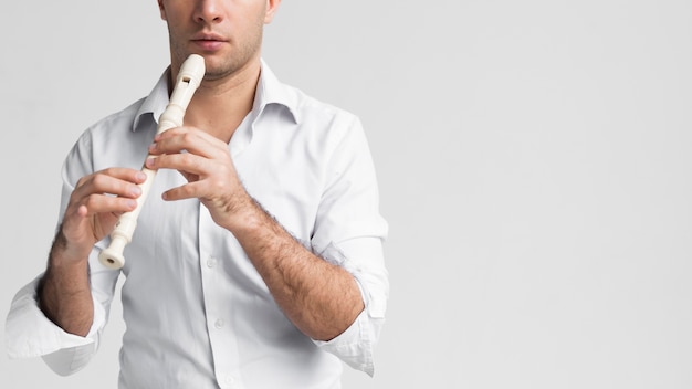 Front view man in white shirt playing the flute