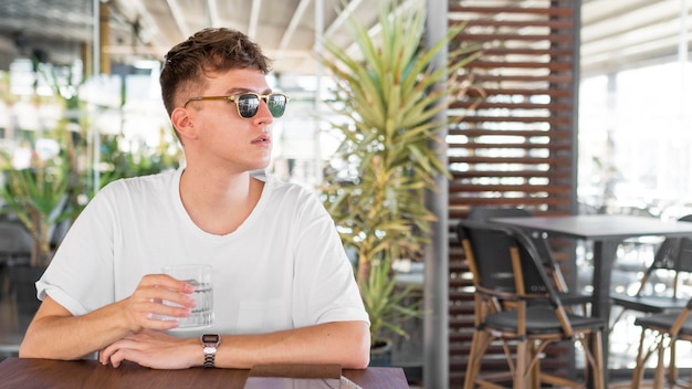 Front view of man with glasses having a glass of water at pub