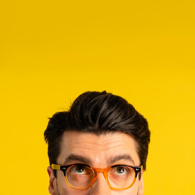Free photo front view of man with glasses looking up with copy space