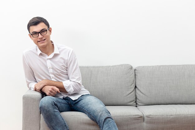 Front view of man with glasses on sofa with copy space