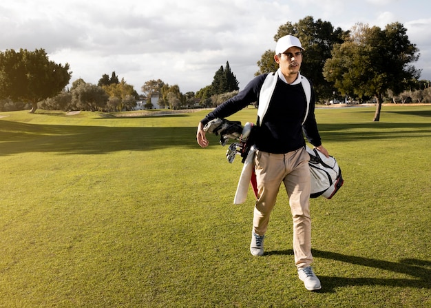 Вид спереди человека с клюшками для гольфа на поле