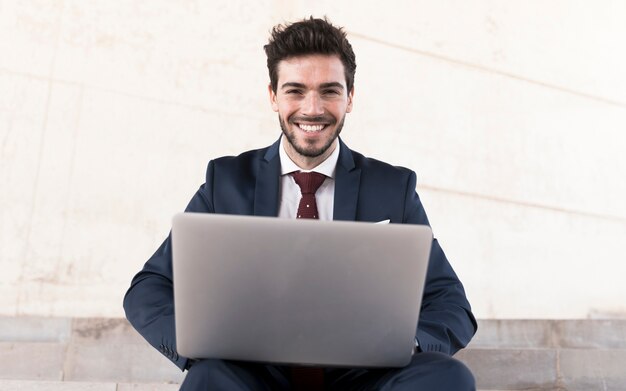 Front view man with laptop looking at camera 