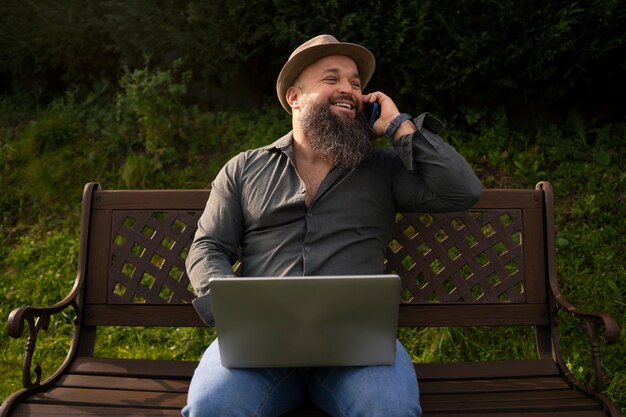 Front view man with laptop outdoors