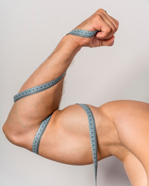 Front view of man with measuring tape over bicep and arm