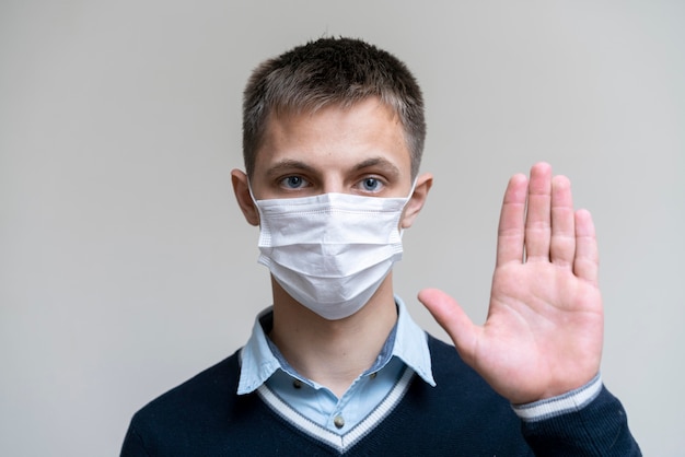 Free photo front view of man with medical mask holding palm up